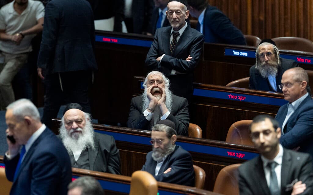 Prime Minister Benjamin Netanyahu seen leaving the Knesset plenum as opposition MKs shout during the draft-law vote