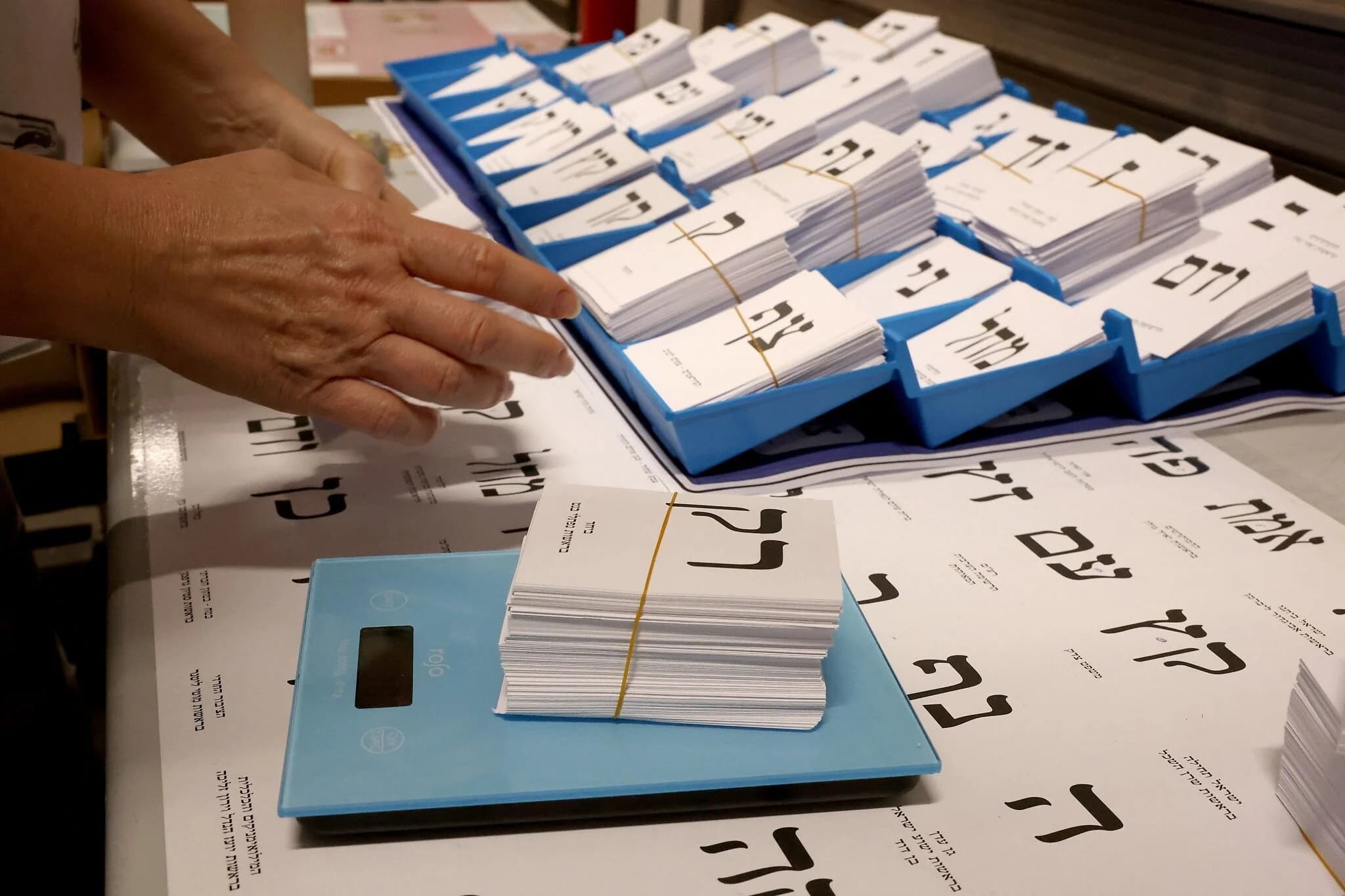 עובד שוקל גיליונות פתקי הצבעה חדשים שהודפסו לקראת הבחירות ב-27 באוקטובר, במפעל דפוס בקרית גת
